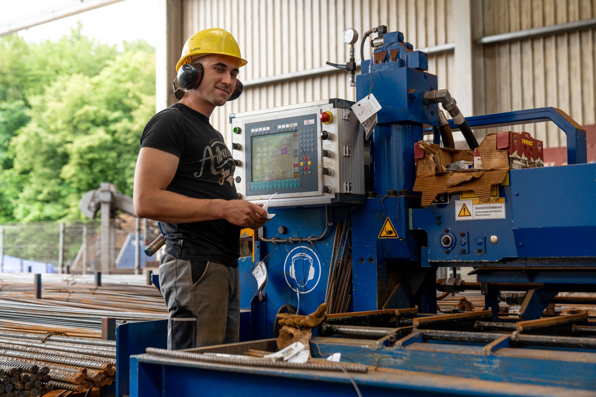 Mitarbeiter mit Schutzhelm und Gehörschutz an einer Maschine in der BLUMENSTOCK-Produktion